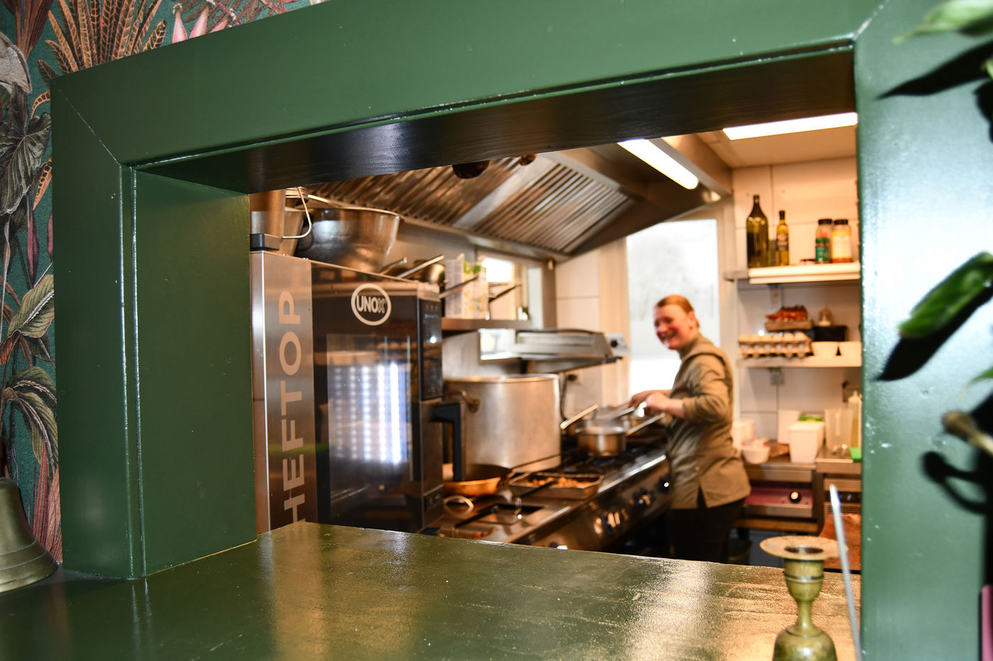 Les Deux Ponts doorkijk naar de keuken waar lachende kok aan het werk is