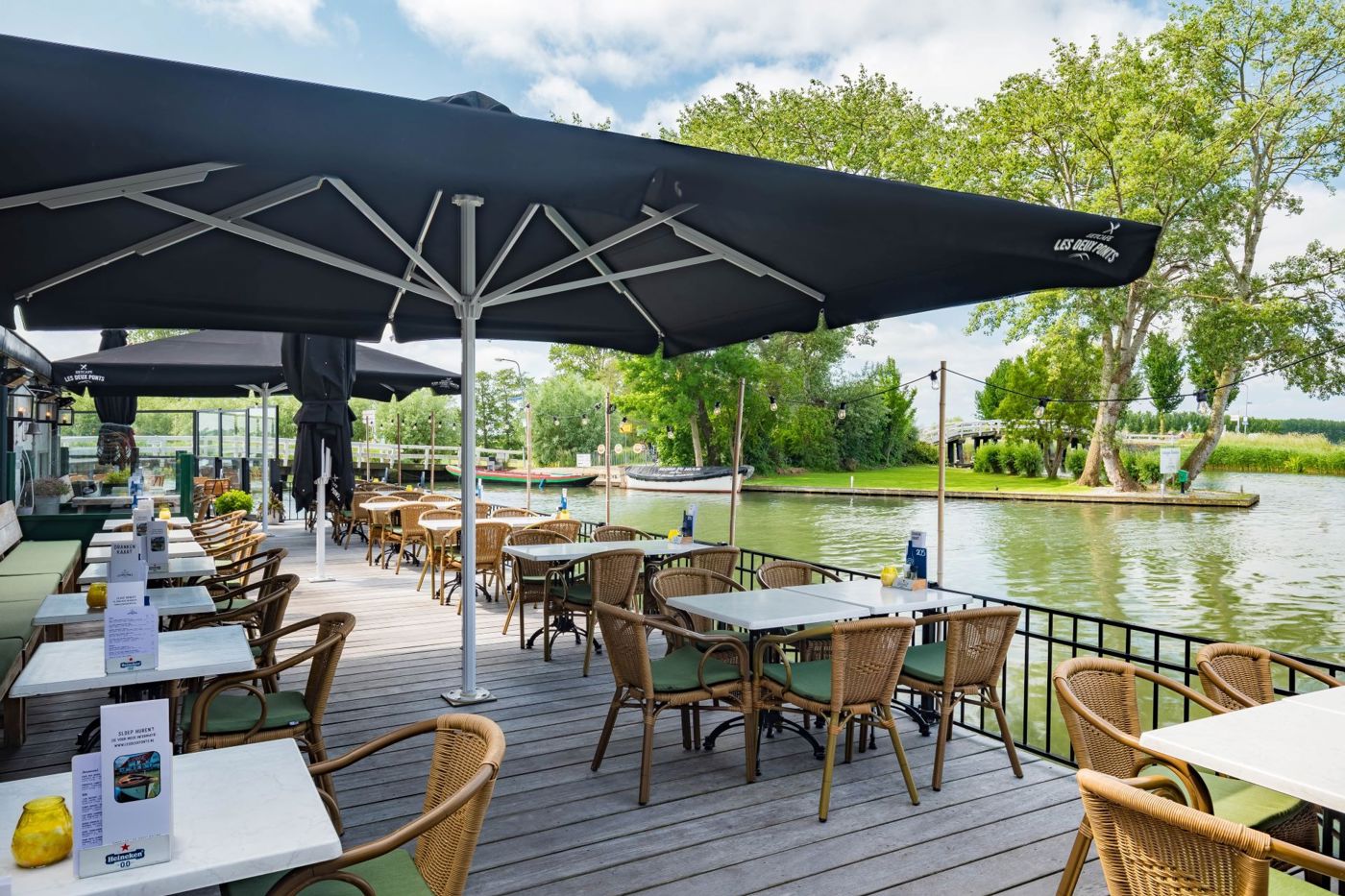 Terras aan het water onder grote parasol bij Restaurant Les Deux Ponts